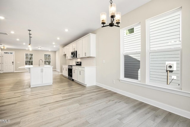 kitchen featuring stainless steel appliances, white cabinets, a healthy amount of sunlight, and a sink