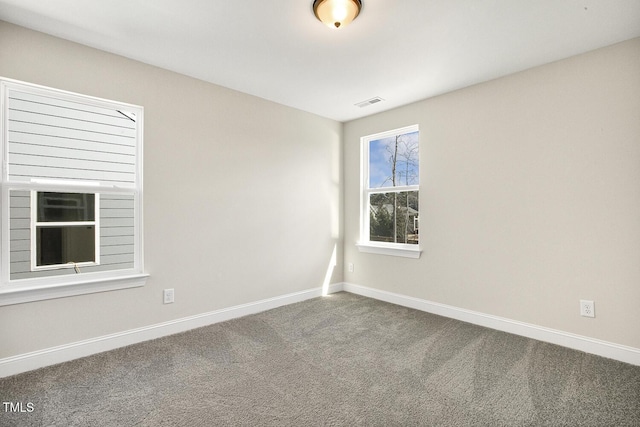 spare room with carpet floors, visible vents, and baseboards