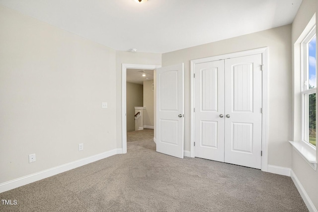 unfurnished bedroom featuring carpet floors, baseboards, and a closet