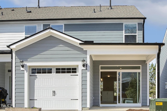 exterior space featuring an attached garage and a shingled roof