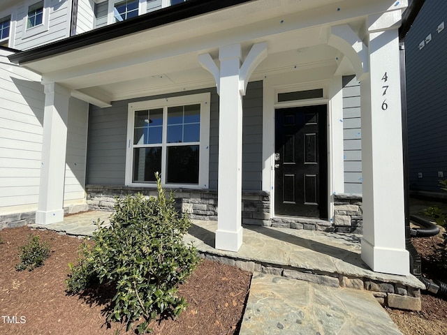property entrance featuring stone siding and covered porch
