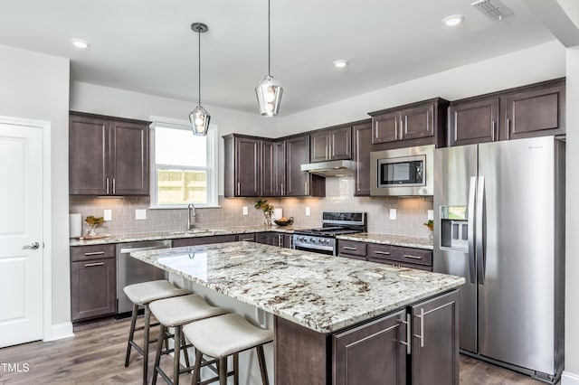 kitchen featuring stainless steel appliances, a kitchen island, tasteful backsplash, and dark wood-type flooring