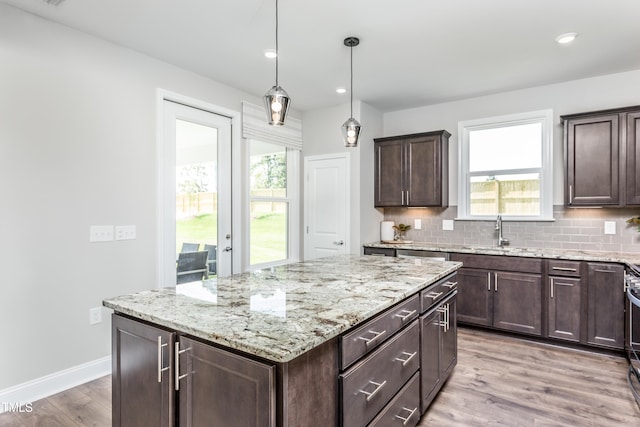 kitchen featuring pendant lighting, a center island, light hardwood / wood-style flooring, tasteful backsplash, and dark brown cabinetry