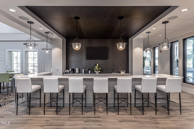 bar with pendant lighting, light wood-type flooring, and a wealth of natural light