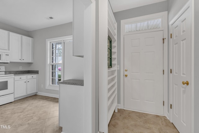 interior space with white cabinets, white appliances, and light tile patterned floors