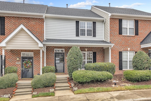 townhome / multi-family property featuring brick siding and roof with shingles