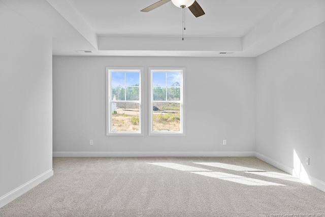 empty room featuring carpet, a raised ceiling, visible vents, a ceiling fan, and baseboards