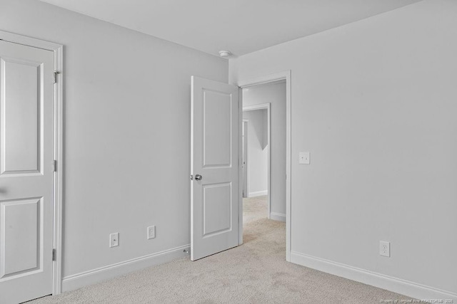 unfurnished bedroom featuring light carpet and baseboards