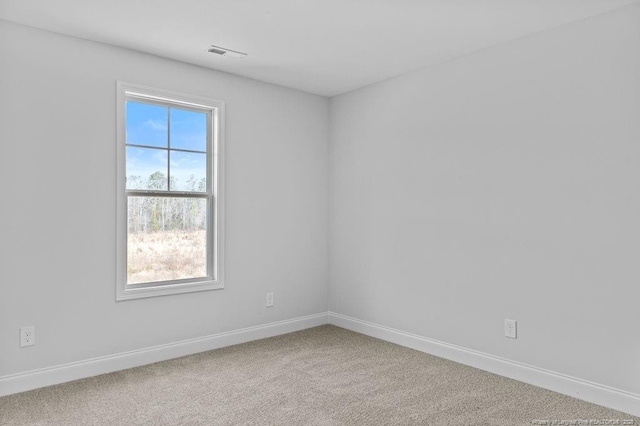 unfurnished room with carpet, visible vents, and baseboards