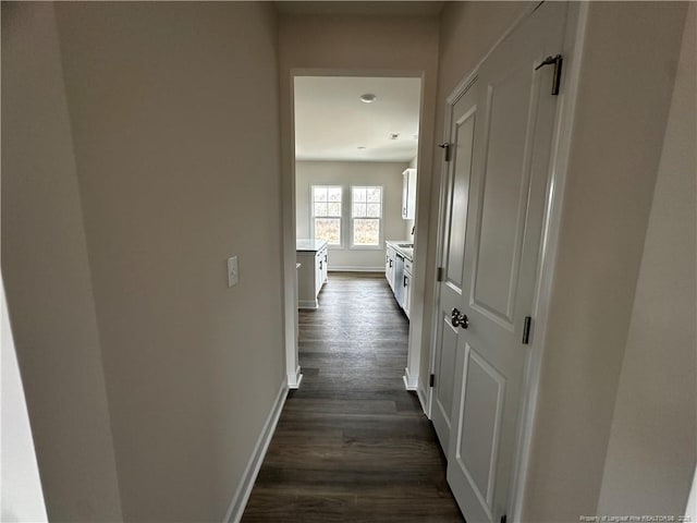 hall with dark wood-style flooring and baseboards