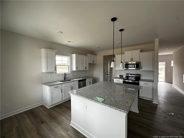 kitchen with stainless steel appliances, a sink, white cabinetry, baseboards, and dark wood finished floors