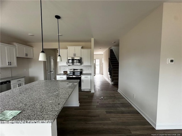 kitchen with backsplash, appliances with stainless steel finishes, white cabinets, light stone countertops, and baseboards