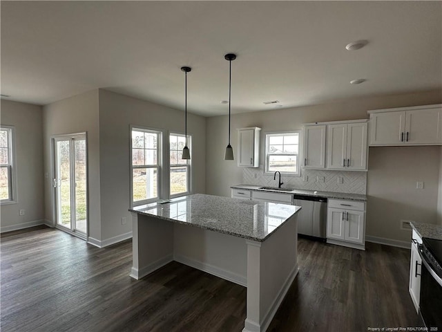 kitchen with a center island, tasteful backsplash, a sink, light stone countertops, and dishwasher