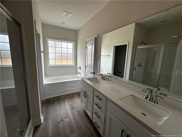 full bathroom with wood finished floors, a sink, a shower stall, and a bath