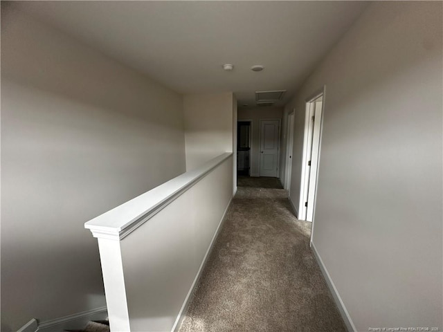 hall featuring attic access, dark carpet, an upstairs landing, and baseboards