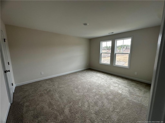 carpeted spare room with visible vents and baseboards