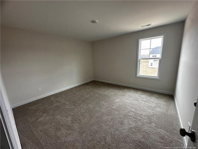 spare room featuring carpet floors, visible vents, and baseboards