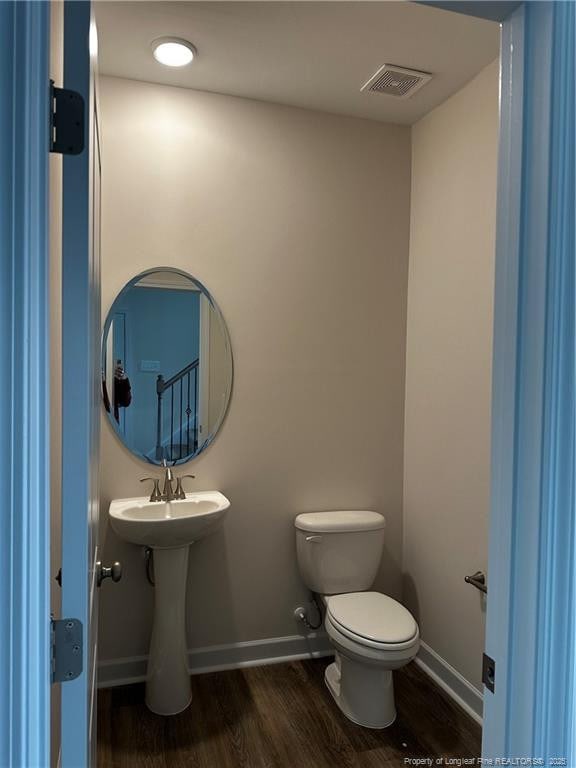 bathroom featuring visible vents, toilet, a sink, wood finished floors, and baseboards