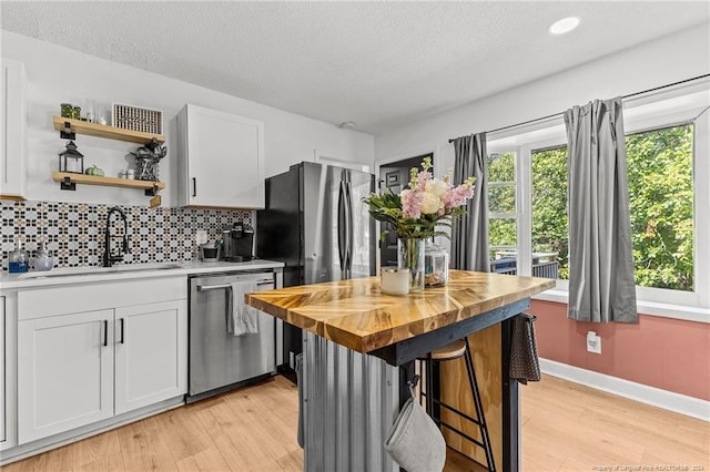 kitchen with white cabinetry, sink, stainless steel appliances, butcher block countertops, and light wood-type flooring