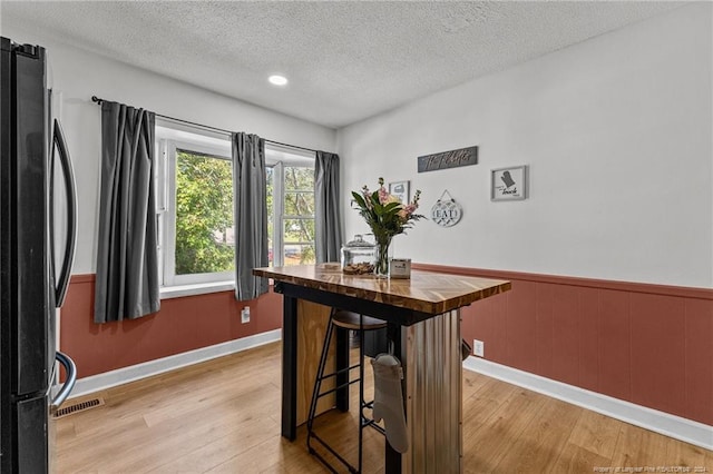 dining area with light wood-type flooring and a textured ceiling