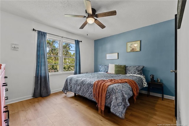 bedroom with ceiling fan, a textured ceiling, and light hardwood / wood-style flooring