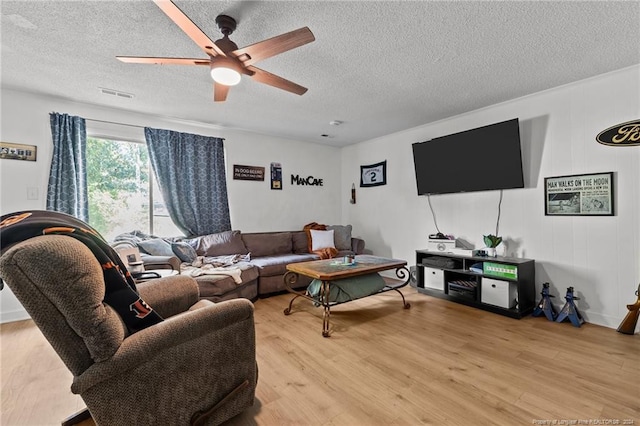 living room featuring a textured ceiling, light wood-type flooring, and ceiling fan