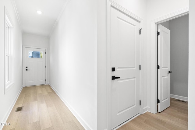 hallway with ornamental molding and light wood-type flooring