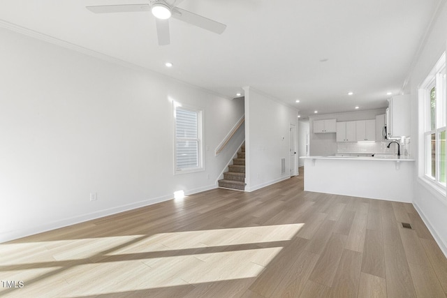 unfurnished living room with light wood-type flooring and ornamental molding