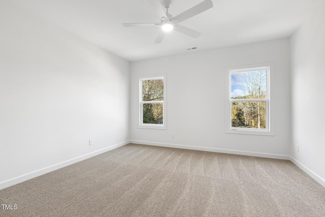 carpeted spare room featuring a wealth of natural light and ceiling fan