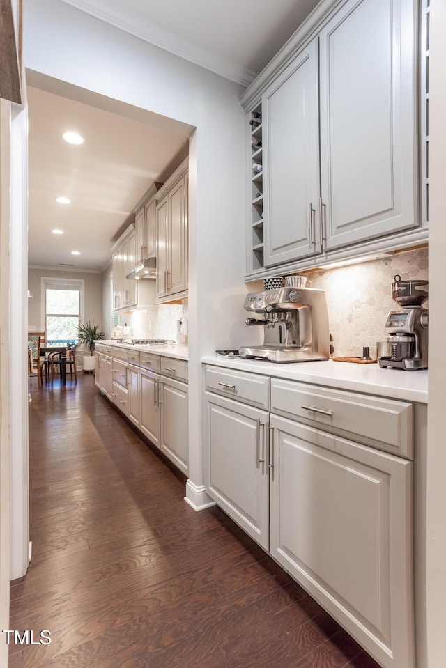 kitchen with decorative backsplash, crown molding, dark hardwood / wood-style floors, and stainless steel gas stovetop