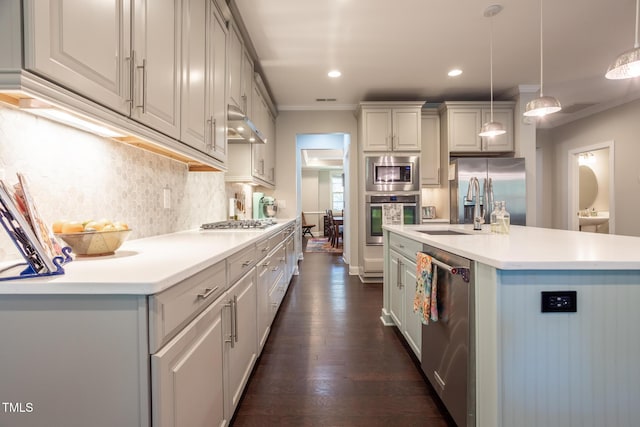 kitchen with dark hardwood / wood-style flooring, stainless steel appliances, sink, pendant lighting, and an island with sink