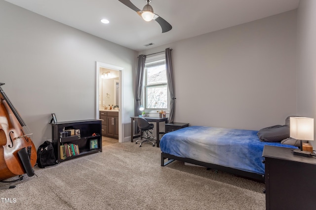 bedroom featuring light carpet, ensuite bathroom, and ceiling fan