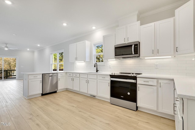 kitchen with kitchen peninsula, white cabinets, stainless steel appliances, and light wood-type flooring