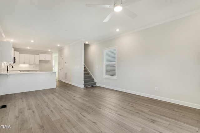 unfurnished living room with ceiling fan, sink, crown molding, and light hardwood / wood-style flooring