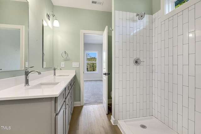 bathroom featuring tiled shower, vanity, hardwood / wood-style flooring, and toilet