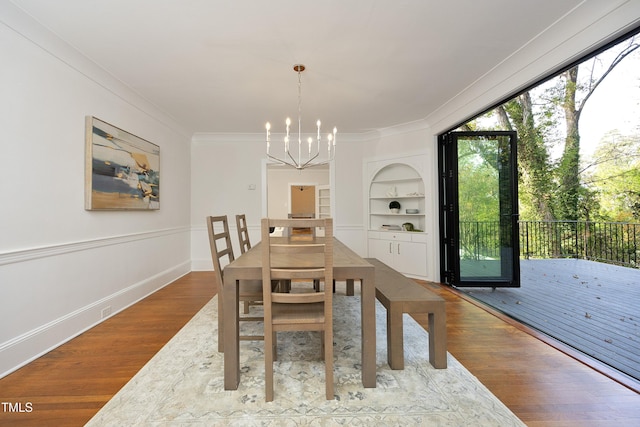 dining space featuring hardwood / wood-style floors, a notable chandelier, built in features, and ornamental molding