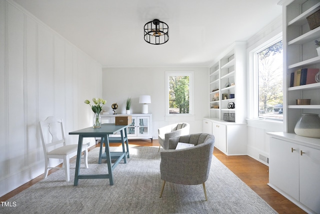 living area featuring built in features, light wood-type flooring, crown molding, and a chandelier