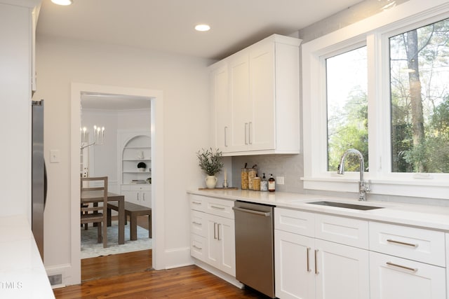 kitchen with dark hardwood / wood-style flooring, sink, a notable chandelier, dishwasher, and white cabinets