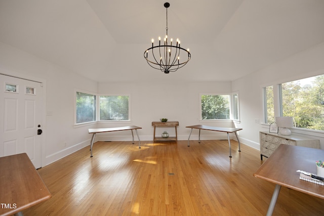 unfurnished dining area with light wood-type flooring, an inviting chandelier, and vaulted ceiling