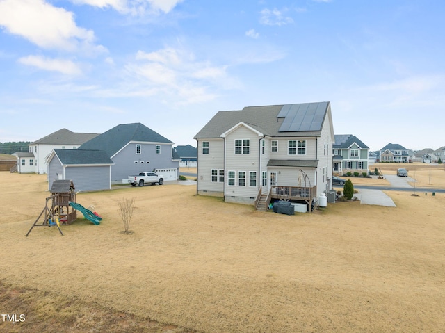 rear view of house featuring a playground and solar panels