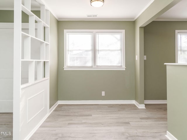 unfurnished dining area featuring light hardwood / wood-style flooring, a wealth of natural light, and ornamental molding