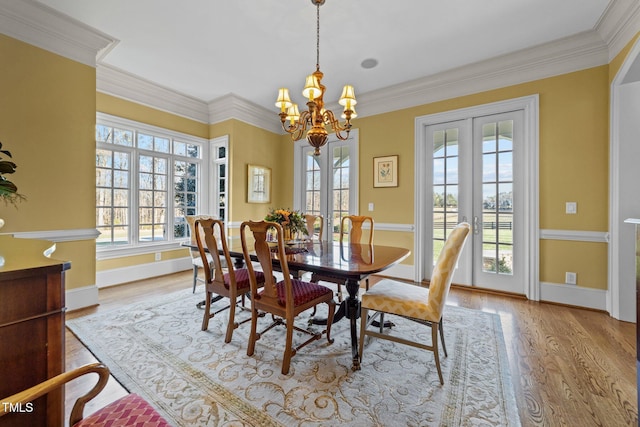 dining area with ornamental molding, french doors, and a chandelier