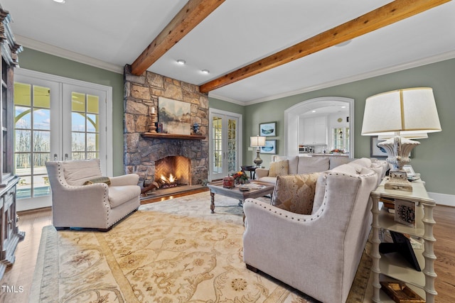 living room with a fireplace, french doors, light hardwood / wood-style floors, and ornamental molding