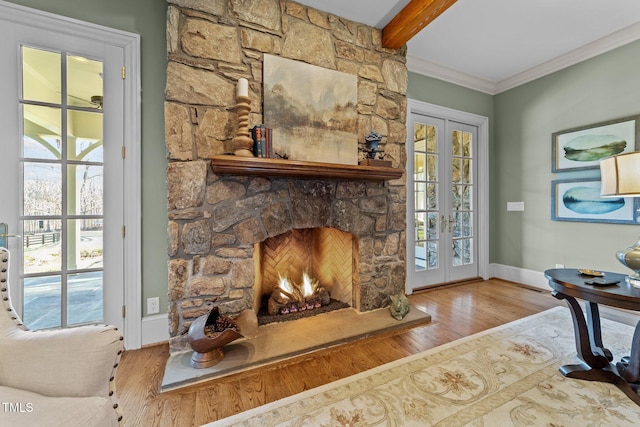 living room featuring a stone fireplace, wood-type flooring, crown molding, french doors, and beam ceiling