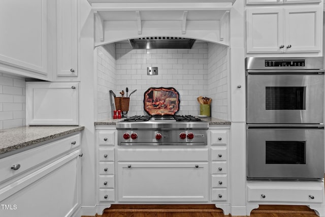 kitchen with stainless steel appliances, white cabinetry, tasteful backsplash, and light stone counters