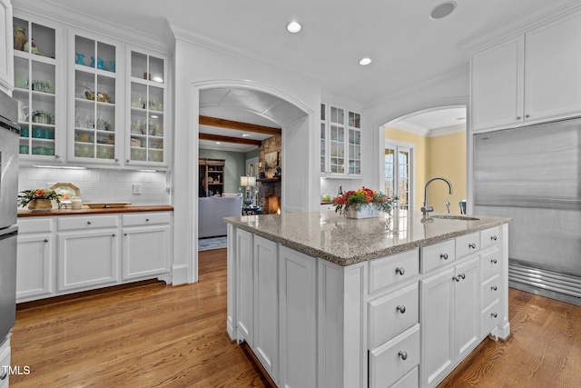 kitchen featuring white cabinets, light stone countertops, light hardwood / wood-style flooring, and sink