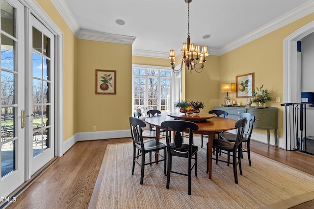 dining room with ornamental molding, light hardwood / wood-style flooring, french doors, and a chandelier