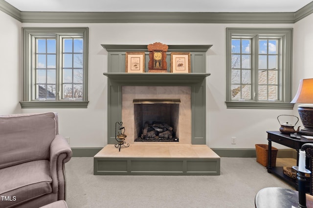 living area featuring a tiled fireplace, ornamental molding, and plenty of natural light