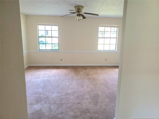 carpeted spare room featuring ceiling fan, a healthy amount of sunlight, and a textured ceiling