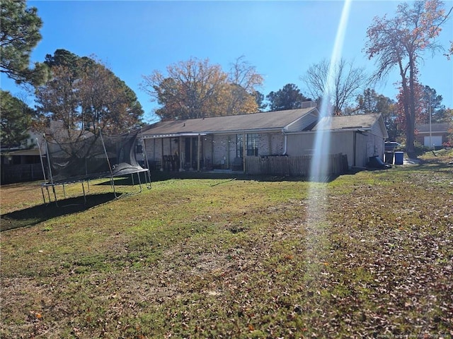 rear view of house featuring a lawn and a trampoline